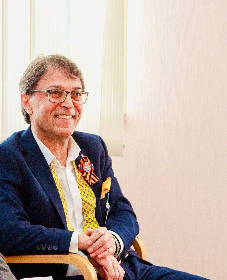 A distinguished English professor seated with an open book